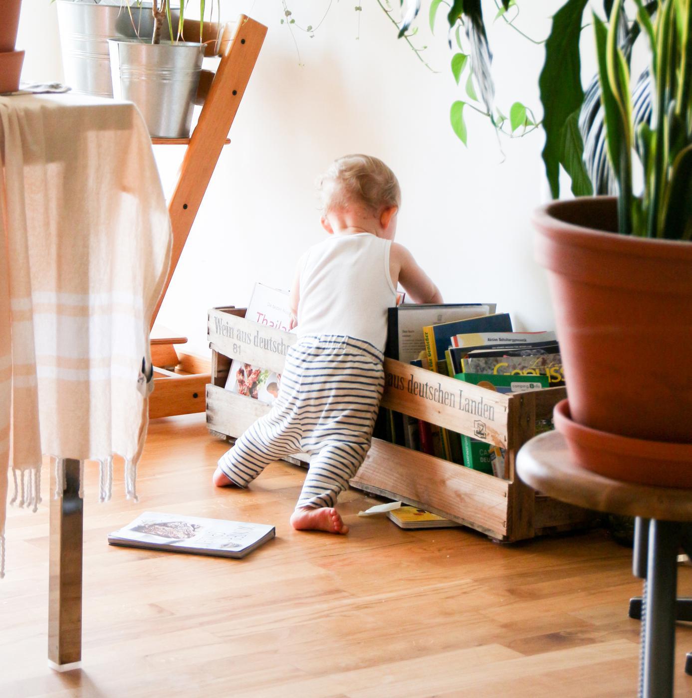 Ein Kleinkind vor einer Kiste mit Bilderbüchern